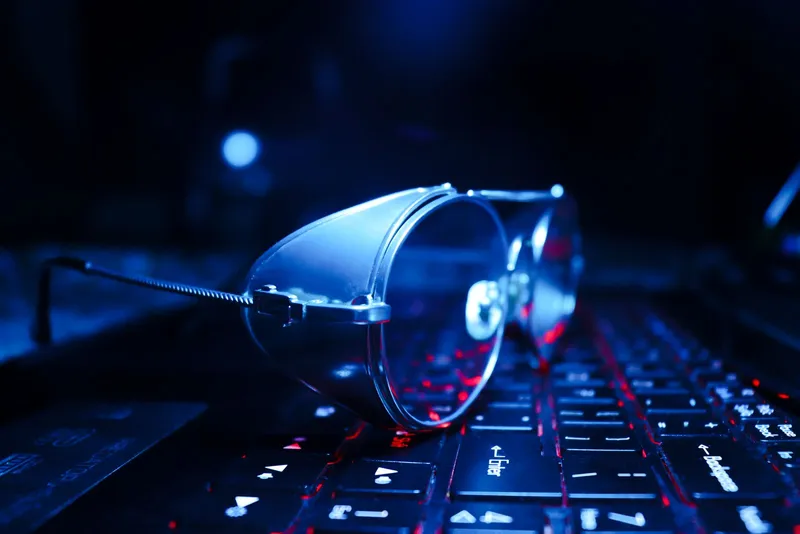 Gafas apoyadas sobre el teclado iluminado de un portátil