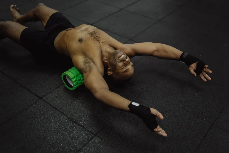 Hombre usando un rodillo de espuma para la recuperación muscular en un gimnasio