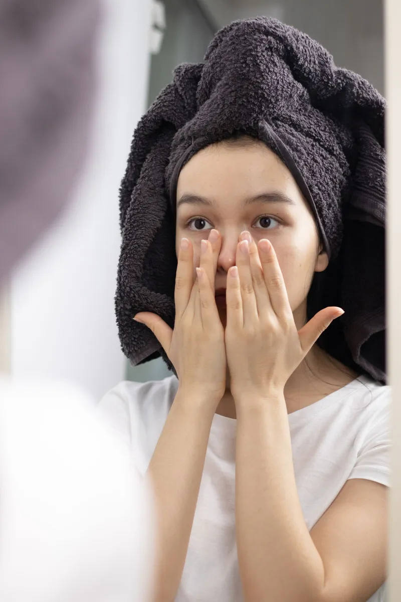 Mujer cuidando su piel frente al espejo en su rutina de belleza en casa