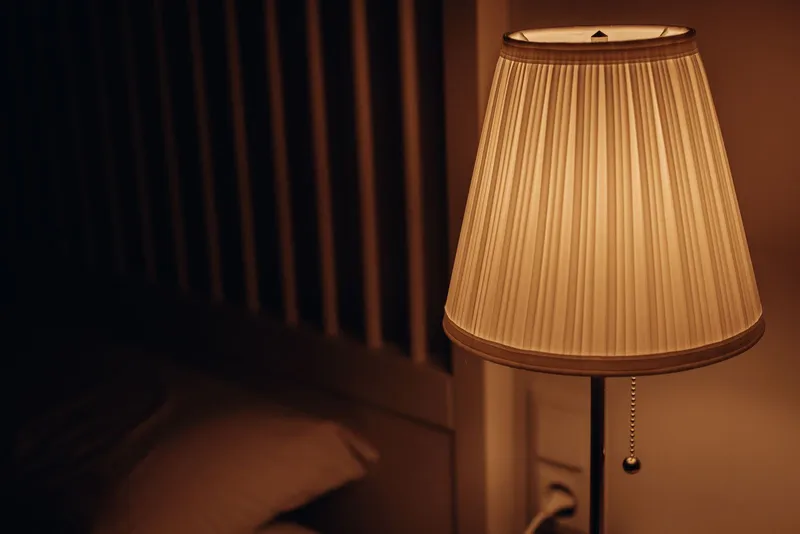 Lámpara de mesilla con luz cálida y tenue creando un ambiente relajante en el dormitorio